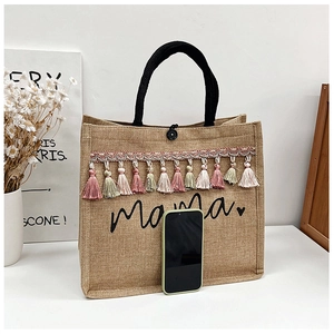 Macro detail of large jute tote with colorful fringe trim and script Mama print