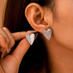 Silver heart-shaped leaf texture stud earrings in stainless steel on model ear