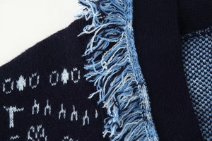 Detail of navy knit cardigan with white jacquard patterns and light blue fringe accents
