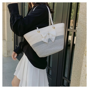 Grey and white woven tote bag with large white bow detail on model in natural light