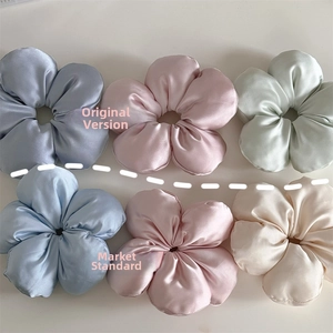 Detail view of six satin flower-shaped scrunchies in pastel blue, pink, and cream colors