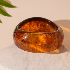Detailed macro of amber resin bracelet on white stone with natural sunlight and shadow