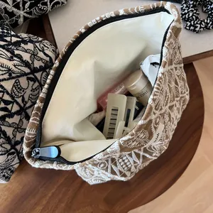Detail of embroidered linen makeup bag showing floral patterns and interior storage space