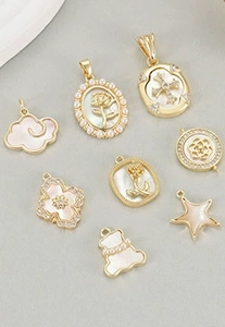 Detailed view of assorted gold charms with white mother of pearl and crystal accents