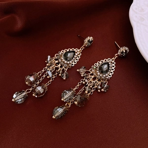 Detailed macro of vintage drop earrings featuring charcoal crystals and gold metal tassels
