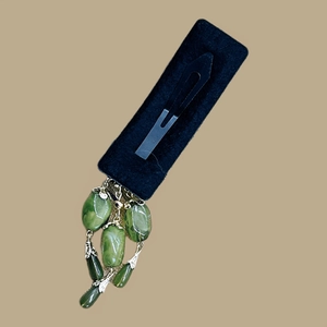Détail d'une pince à cheveux vert émeraude avec glands cloches et base métallique