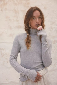 Detail showing waffle knit texture, lettuce trim hem, and thumbholes on grey long sleeve top