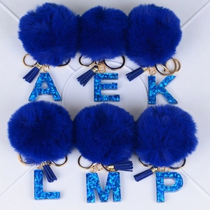 Detail of blue pompom initial keychains with glitter letters and matching tassels