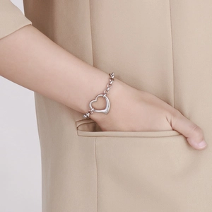 Dettaglio di un bracciale minimalista in argento con ciondolo a cuore al polso