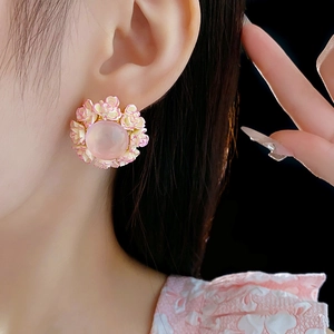Detailed close-up of a pink floral stud earring with enamel petals on a gold-tone base