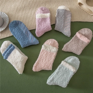 Detailed close-up of fluffy coral fleece socks with anti-slip silicone grips in pastel colors