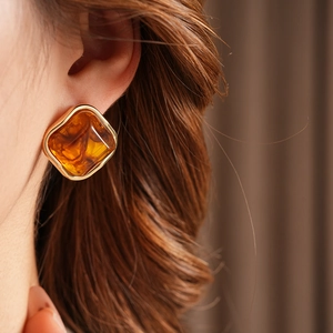 Close-up of a vintage geometric amber square earring with a gold metal edge on ear