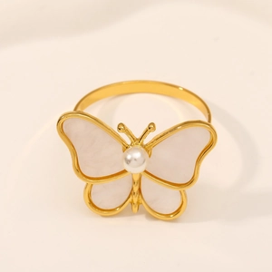 Macro detail of golden dragonfly napkin ring with white enamel wings and pearl inlay