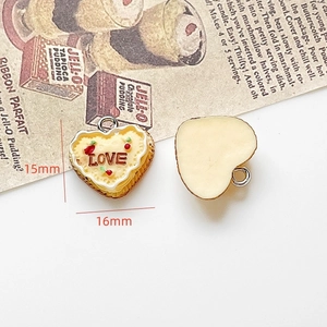 Detail showing cream heart cake charm with LOVE text and strawberry dots for DIY jewelry