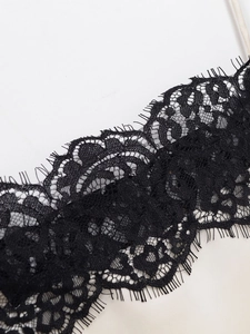 Macro view of delicate black eyelash lace trim over cream satin fabric top detail