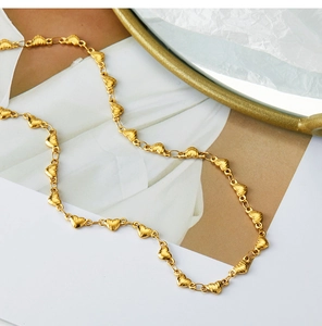 Detailed view of 18K gold plated heart-shaped link chain on textured art paper