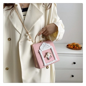 Detailed view of pink embossed bag with cherub relief and elegant pearl strap