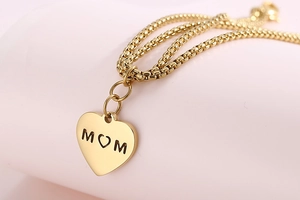 Macro shot of gold heart-shaped pendant with MOM cutout detail for Mother's Day gift
