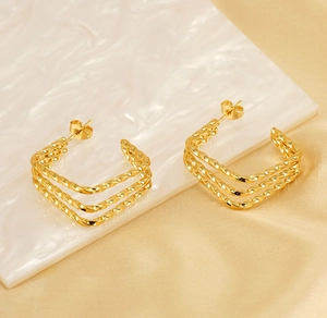 Detailed view of 18k gold plated twisted triple-layer geometric earrings on satin fabric
