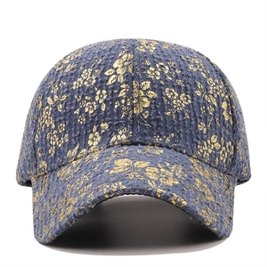 Detail view of vintage denim baseball cap with gold flower patterns and blue tweed texture