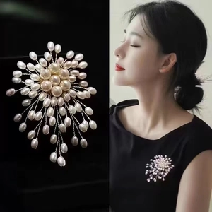 Elegant handmade pearl brooch in radial firework design shown on dark garment and flat lay