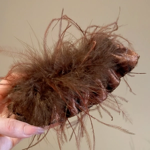 Detailed view of a brown faux ostrich feather claw clip with metallic shimmer finish