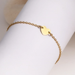 Vue détaillée d'un bracelet doré avec breloque cœur sur un support cylindrique blanc