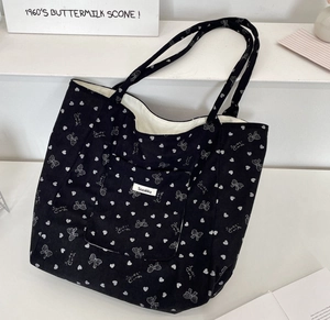 Detail of black corduroy tote bag showing heart prints and soft fabric texture
