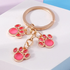 Detail of cute cat paw keychains with pink enamel charms on gold plated rings
