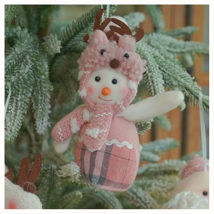 Detailed view of a pink plush snowman ornament with knitted reindeer hat on snowy pine branch