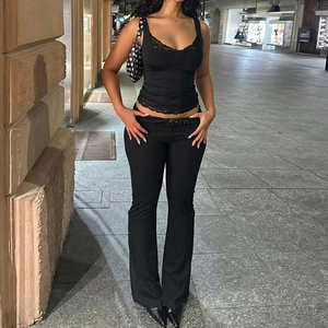Camisole noire en dentelle avec pantalon évasé sur une rue de la ville pendant la nuit
