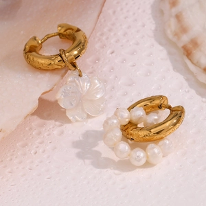 Detailed close-up of 18K gold earrings with asymmetric pearl and shell flower design