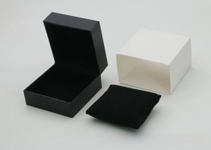 Detail view of black faux leather watch box with white sleeve and velvet pillow