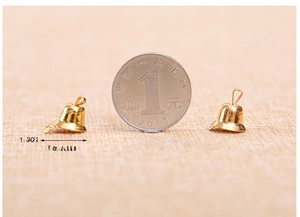 Close-up of 1.2cm small golden metal craft bells compared with a coin for size reference
