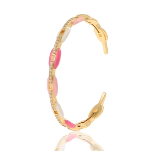 Detailed view of golden open bangle with pink enamel and white zircon inlay