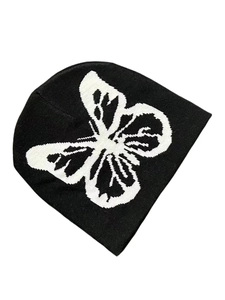 Close-up of black and white knitted beanie featuring a large butterfly jacquard pattern