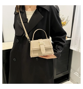 Fashionable beige crossbody bag styled on a black trench coat for a trendy commute look