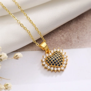Gros plan du pendentif cœur doré serti de zircons bleu foncé sur de la soie blanche