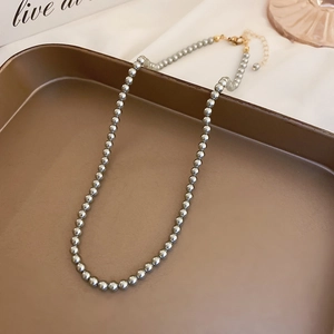 Metallic grey pearl necklace with gold lobster clasp and extension chain shown in a bronze tray