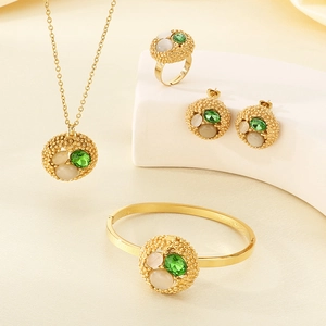 Detailed view of vintage gold jewelry set featuring green gemstones and beaded texture