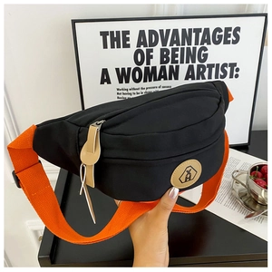Detail of black canvas chest bag with vibrant orange nylon strap and leather logo patch