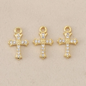Macro detail of three gold-plated baroque cross pendants with sparkling rhinestones