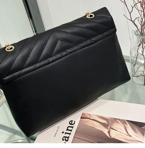 Detail of black chevron quilted crossbody bag with gold metal chain eyelets