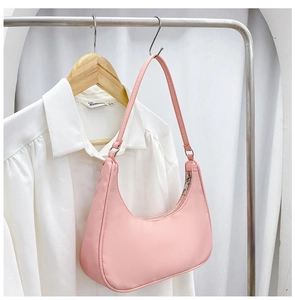 Detailed view of a pink nylon hobo shoulder bag with zipper hanging next to a white shirt