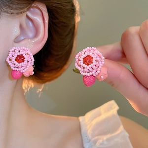 Close-up of handmade pink beaded flower earrings with central red gem detail