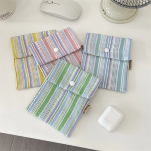 Close-up of four colorful striped fabric pouches with snap closures on a white desk