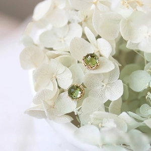925 silver peridot stud earrings in gold crown setting on white flower petals
