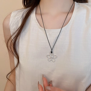 Gros plan d'un collier pendentif fleur évidée en argent avec un cordon noir
