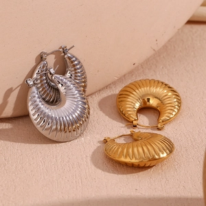 Macro shot of 18K gold and silver hollow geometric earrings with radial textured finish