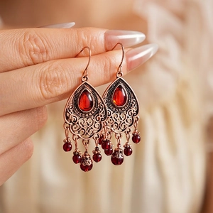 Vintage copper teardrop earrings with red ruby stones and beaded tassels in hand